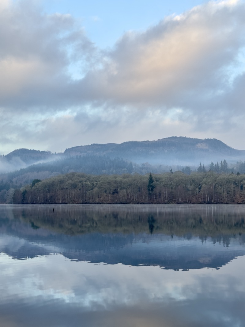 Mirror lake reflecting misty mountains