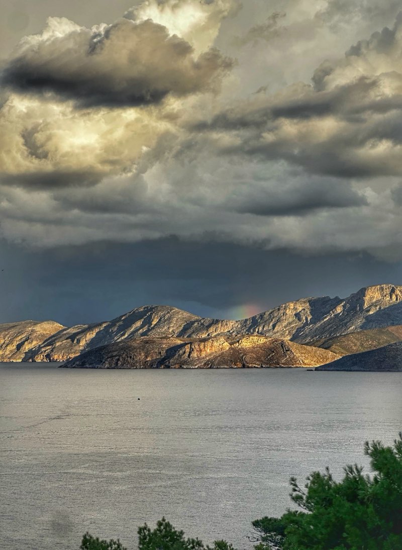 Stormy clouds over sunlit coastal mountains